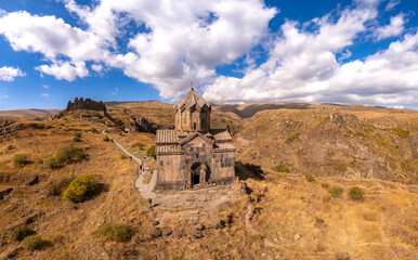 Fototapeta premium Aerial drone view of famous Vahramashen Church of the 11th century, located near destroyed Amberd fortress in sunny summer day. Cliff with Arkashian River deep in canyon. Aragatsotn region, Armenia