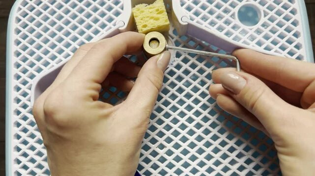 working with a sanding machine for stained glass top view of female hands with a piece of colored blue glass splashes of water and sanding with an emery cylinder