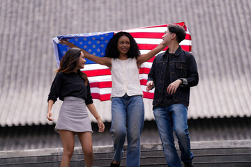 Diverse group of friends proudly holding an American flag outdoors, symbolizing unity and patriotism. Their smiles and casual poses embody freedom, friendship, and the spirit of togetherness.