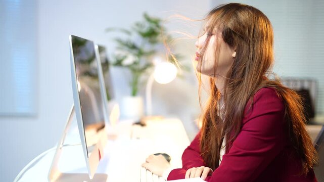 Stressed businesswoman touches her hair while staring at the computer screen. Frustration and anxiety are evident as she navigates the pressures of her work environment