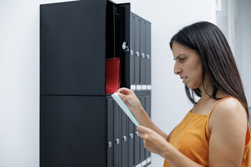 A young single woman opens the mailbox on her porch and receives bad news in the mail.