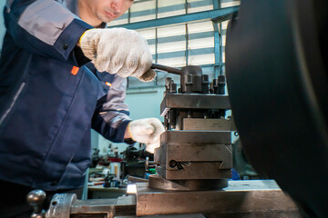 Close up view of a factory worker operating heavy industrial machinery with focus on precision. Gloved hands adjust the controls in a mechanical workshop, emphasizing safety, expertise, and metalwork.