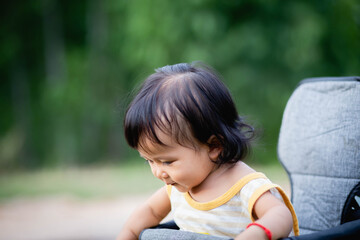 Young asian woman mother, walking with baby stroller in park