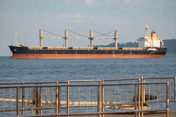 A beautiful view of the cargo ship in the blue ocean seen from the pier waiting for shipping heavy supplies across the countries.