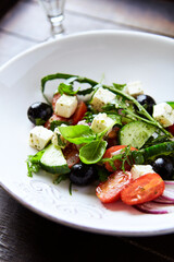 Healthy Salad with Feta Cheese, Black Olives, Cucumber and Cherry Tomatoes. Wooden background. Close up.