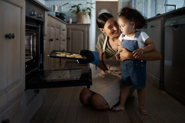 Cookies, mom or toddler baking with oven, tray or food for bonding or lesson in family home. Happy parent, night or mother teaching kid cooking skill for child development, learning or breakfast meal