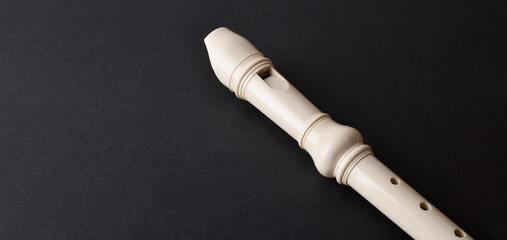 Detail of white plastic recorder on black table © Davizro Photography