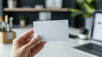 A person holds a blank business card in a soothing office environment suggesting a moment of preparation for a networking opportunity or personal branding