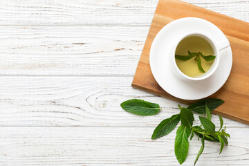 Cup of mint tea on table background. Green tea with fresh mint top view with copy space