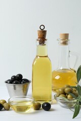 Bottle of fresh olive oil and olives with leaves on the table