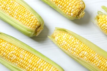 Fresh corn on cobs on wooden background, top view