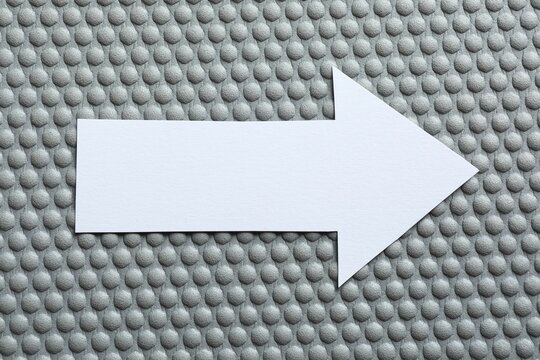Paper arrow on color background, top view