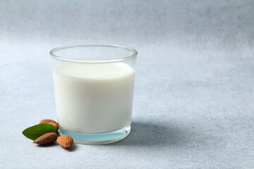 Glass of almond milk on gray background