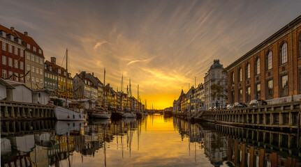 Sunrise over Nyhavn Canal in Copenhagen light and buildings reflect in the calm water