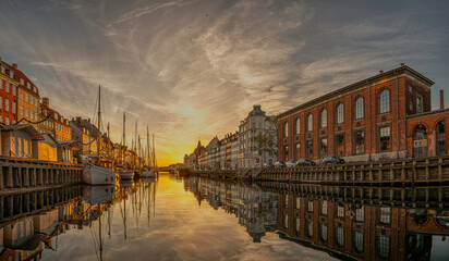 Sunrise over Nyhavn in Copenhagen with reflections in the mirrored canal