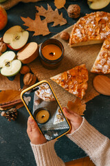 Girl taking photo on phone, candle and homemade apple pie, autumn mood