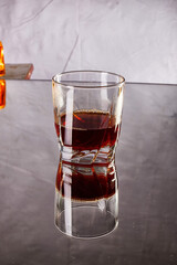 A close-up view of a glass filled with dark liquid on a reflective surface showcasing ambient lighting in a cozy setting