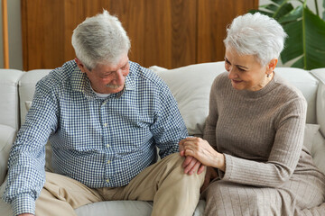 Senior adult mature couple in love holding hands at home. Mid age old husband and wife looking with tenderness love enjoying wellbeing. Grandmother grandfather together. Family moment love and care