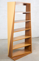 Vintage twisted bookshelf with cascading widths. Made from a mix of woods - teak, walnut, and beech wood grain.s. Interior product photograph.