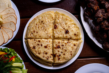 A stack of traditional Caucasian flatbreads with stuffing (khychiny) with mashed potatoes, cottage cheese and herbs. View from above.