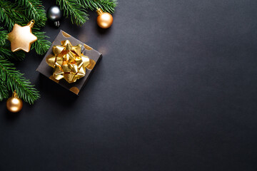 Christmas present box at black background. Christmas card with white and golden decorations, flat lay image.