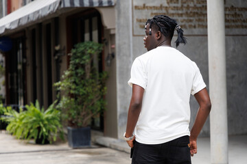 Candid of African man model with dreadlocks hairstyle wearing white t-shirt standing in the city