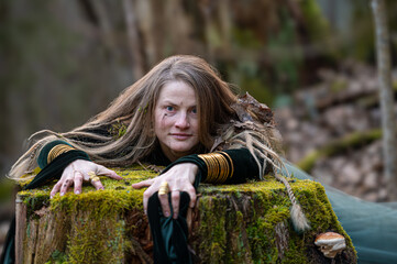 Woman leaning on tree trunk in forest. Shallow depth of feld