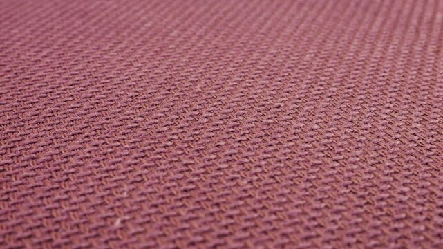 Relief, textured textile background made of purple color grape shade cotton fabric on a rotating display case. Sewing, fashion and clothing design. Close-up view.
