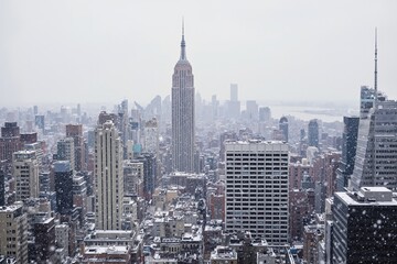 Snowfall over new york city skyline featuring iconic skyscrapers and urban landscape.