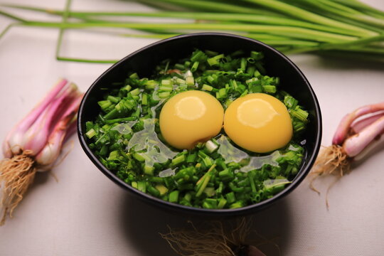 bowl of egg yolks isolated on white background, top view with green vegetables.close up image of two eggs yolk in a bowl are one of the food ingredients on the restaurant table in the kitchen .