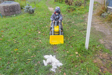 a child boy on a wheeled bulldozer tractor removes snow with a snow plow, photo without filters