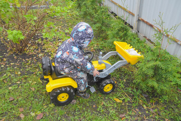 a child boy on a wheeled bulldozer tractor removes snow with a snow plow, photo without filters