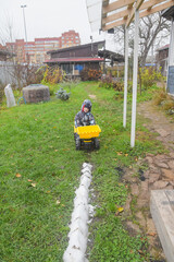a child boy on a wheeled bulldozer tractor removes snow with a snow plow, photo without filters