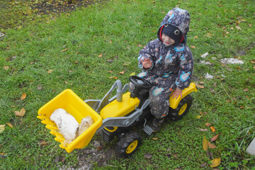 a child boy on a wheeled bulldozer tractor removes snow with a snow plow, photo without filters