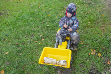 a child boy on a wheeled bulldozer tractor removes snow with a snow plow, photo without filters