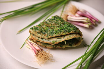 Stuffed omelette with tomatoes and spinach on white plate.Herb omelette with chives and oregano sprinkled with chili flakes, garlic panini toasts.Omelette with salad and tomatoes on plate
