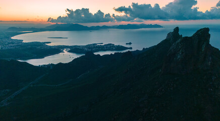 Sunrise from the peak of Tetakawi Mountain before the sun rises. The sky is painted in warm tones on the horizon, while the calm sea of San Carlos Sonora, Mexico still maintains its cool blue tones. 