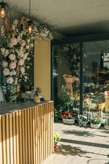 Flower shop interior with a wooden counter decorated with small pumpkins, vases, and plants. The background shows floral arrangements, bouquets