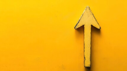A yellow wall with a weathered upward arrow, indicating direction or movement.