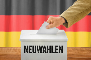 Mann wirft einen Stimmzettel in Wahlurne - Neuwahlen