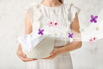 Woman holding wicker basket with towel on light background