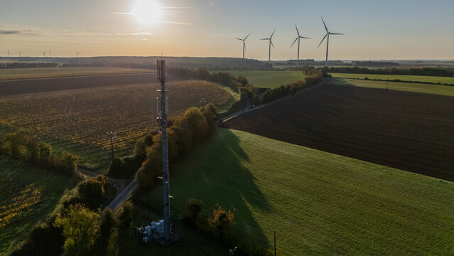 Sunset Over Rural Landscape with 5G Tower and Wind Turbines