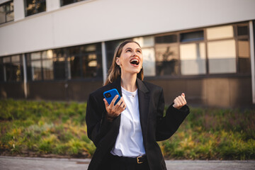 Happy delighted satisfied business woman looking smartphone mobile phone gesturing yes winning pose...