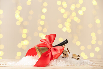 Christmas bell with red bow on white wooden table against blurred lights