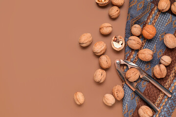 Natural walnuts with nutcracker on brown background