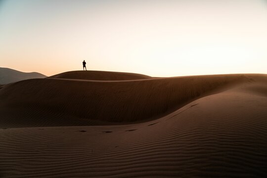 Silhouette shot of a man standing on the Longotoma dunes watching sunset in Valparaiso Region, Chile