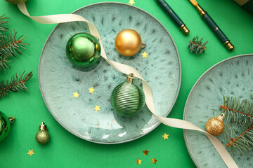 Beautiful table setting with Christmas balls and fir branches on green background
