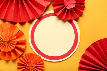 Blank card with paper fans on orange background. New Year celebration