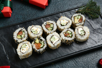 Plate with tasty sushi rolls for Christmas party on dark background, closeup