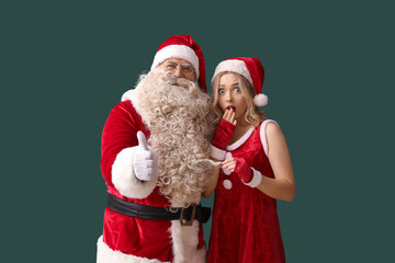 Santa Claus with shocked woman showing thumb-up on green background